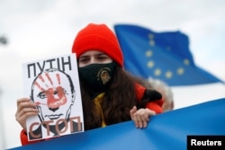 A young woman holds a drawing of Russian President Vladimir Putin during an anti-war protest following Russia's invasion of Ukraine, in Niksic, Montenegro, March 6, 2022.