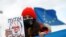 A young woman holds a drawing of Russian President Vladimir Putin during a protest against Russia's invasion of Ukraine in Niksic, Montenegro, on March 6, 2022.