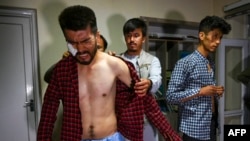 FILE - In this picture taken on Sept. 8, 2021, Afghan newspaper journalist Nematullah Naqdi, left, reacts as his colleagues help him dress in their office in Kabul after being released from Taliban custody after covering a protest in the Afghan capital.