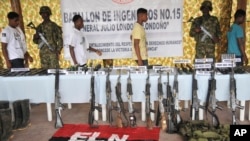Los rebeldes desmovilizados caminan detrás de las armas que entregaron en una base militar en Tarido, Colombia, el domingo 7 de diciembre de 2008.