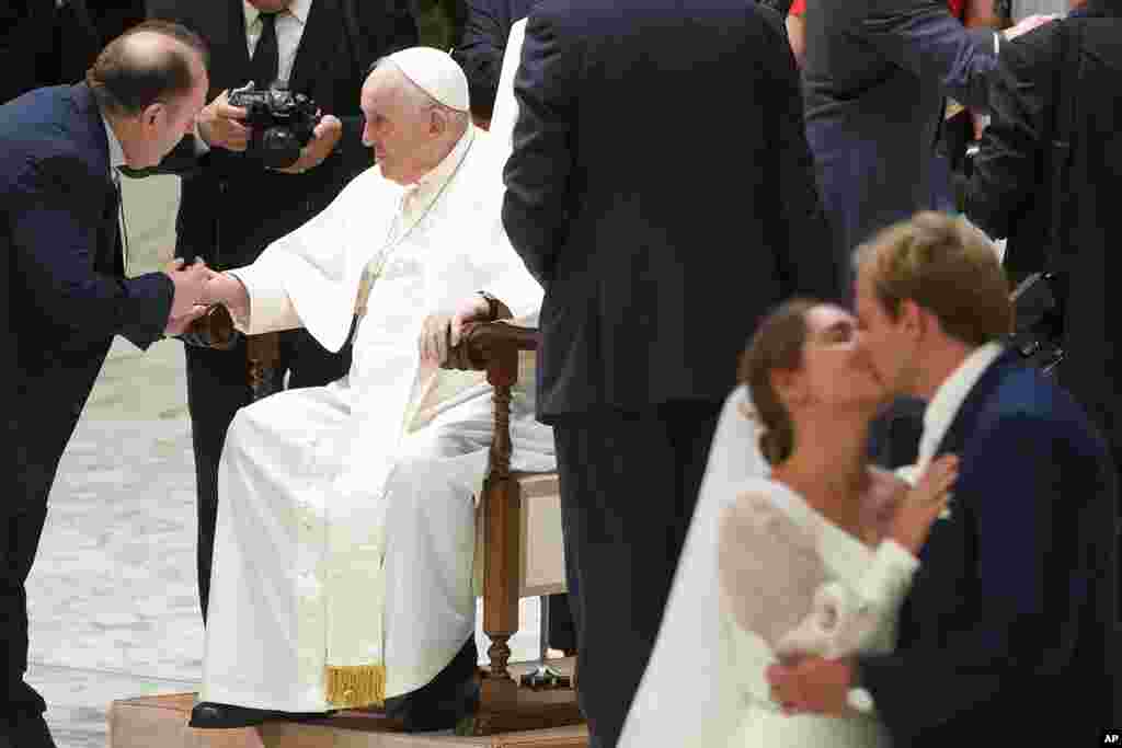 A newly married couple kisses during Pope Francis's weekly general audience in the Paul VI Hall at The Vatican.