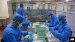FILE - Employees pack boxes containing vials of Covishield, a version of the AstraZeneca vaccine, at the Serum Institute of India in Pune, Nov. 22, 2021.