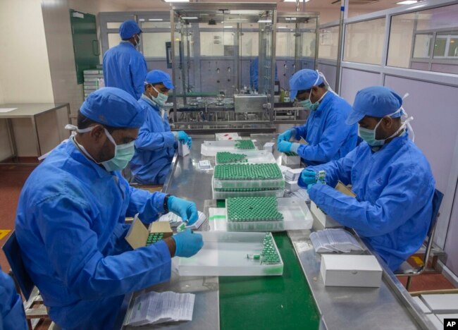 FILE - Employees pack boxes containing vials of Covishield, a version of the AstraZeneca vaccine, at the Serum Institute of India in Pune, Nov. 22, 2021.