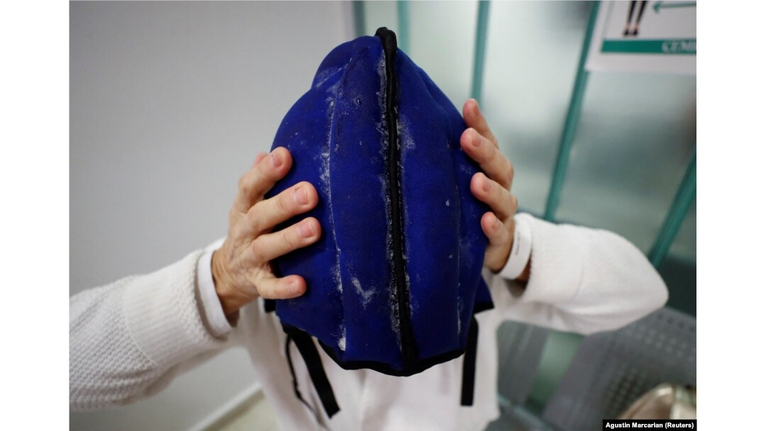 Pasien kanker Elsa Ram sedang memasang helm darurat dari kantong es yang mencegah kerontokan rambut, selama sesi kemoterapi, di Buenos Aires, Argentina 4 Agustus 2022. (Foto: REUTERS/Agustin Marcarian)