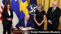 Predsednik SAD Džo Bajden potpisuje Protokol o pristupanju Švedske i Finske NATO-u, u društvu potpredsednice Kamale Haris, švedske ambasadorke Karin Olofsdoter i finskog ambasadora Mika Hautale, 9. avgust 2002. 