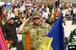 A Ukrainian officer salutes as he attends a ceremony for Ukraine's fallen soldiers of Ukraine at Lychakiv Cemetery in the western Ukrainian city of Lviv, Aug. 24, 2022, marking six months since the start of Russia's invasion of Ukraine, and Ukrainian Independence Day.