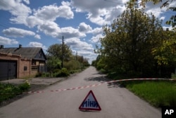 FILE - A sign that reads "Mines" placed on a road where unexploded devices were found after shelling of Russian forces in Maksymilyanivka, Ukraine, May 10, 2022.