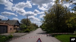 Znak sa natpisom "Mine" postavljen na putu na kojem su pronađene neeksplodirane naprave nakon granatiranja ruskih snaga u Maksimiljanovki, Ukrajina, 10. maja 2022. godine. 