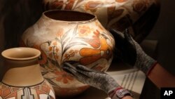 Finishing touches are made on a community-curated exhibition of Native American pottery from the Pueblo Indian region of the U.S. Southwest on July 28, 2022, at the Museum of Indian Arts and Culture in Santa Fe, N.M. (AP Photo/Morgan Lee)