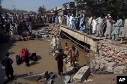 People stand around a washed-out road after heavy rains caused massive flooding, in Charsadda, Pakistan, Aug. 30, 2022.