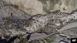 FILE - Receding floodwaters flow past sections of North Entrance Road washed away at Yellowstone National Park in Gardiner, Montana, June 16, 2022.