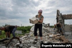 Volunteers clear rubble of a house, destroyed by Russian bombardment, in the village of Novoselivka, Ukraine, Aug. 13, 2022. (AP Photo/Evgeniy Maloletka)