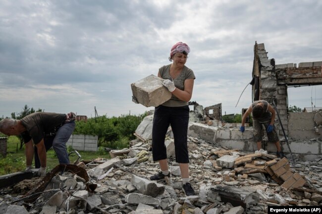 Volunteers clear rubble of a house, destroyed by Russian bombardment, in the village of Novoselivka, Ukraine, Aug. 13, 2022. (AP Photo/Evgeniy Maloletka)