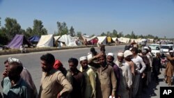 在巴基斯坦查尔萨达，因洪灾而流离失所的人们正在排队领取食物。(2022年8月29日)