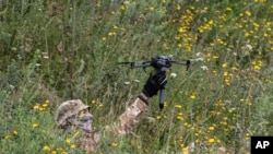 A volunteer soldier holds up a drone used for explosives at a training area near Kyiv, Ukraine, Aug. 27, 2022. Fighters from Chechnya are aiding both sides of the conflict in Ukraine.