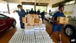 FILE - Firefighters and recruits for the Jackson, Miss., Fire Department carry cases of bottled water to residents vehicles, Aug. 18, 2022, as part of the city's response to longstanding water system problems.