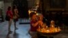 A child is held by his grandmother as they light a candle in a church in Lviv, Ukraine, Aug. 26, 2022.