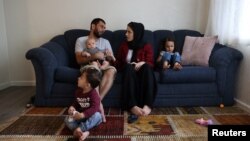 The Mohammadi family, Najib holding Yusuf, Yasar, Susan and Zahra, sit together in their living room, at their home in Sacramento, California, Aug. 1, 2022.