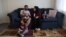 The Mohammadi family, Najib holding Yusuf, Yasar, Susan and Zahra, sit together in their living room, at their home in Sacramento, California, Aug. 1, 2022.