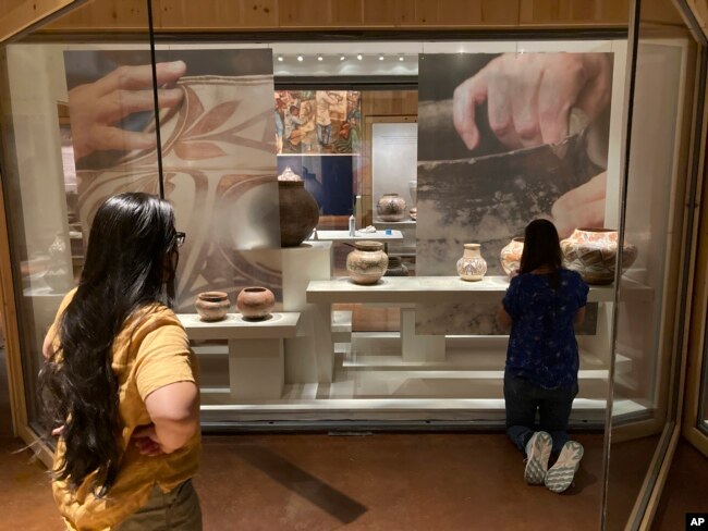 Elysia Poon, director of the Indian Arts Research Center in New Mexico, at left, oversees finishing touches on a community-curated exhibition of Native American pottery from the Pueblo Indian region of the U.S. Southwest on July 28, 2022, at the Museum of Indian Arts and Culture in Santa Fe, N.M. (AP Photo/Morgan Lee)