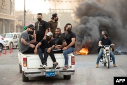 Supporters of Iraqi Shiite cleric Muqtada al-Sadr gather on a road blocked with burning tires during a demonstration in Iraq's southern city of Basra, Aug. 29, 2022.