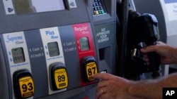 FILE - A customer pumps gas at an Exxon gas station, May 10, 2022, in Miami.