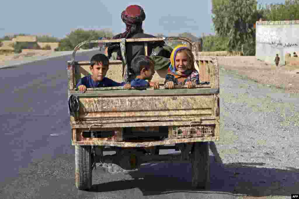 Children travel at the back of a vehicle along a street in Kandahar, Afghanistan, Aug. 29, 2022.