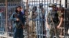 FILE - A Pakistani paramilitary soldier, right, and a Taliban fighter stand guard on their respective sides at a border crossing point between Pakistan and Afghanistan, in Torkham, in the Khyber district of Pakistan, Aug. 21, 2021. 