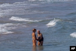 Women cool off on Puerto de Sagunto beach, east Spain, Aug. 16, 2022.