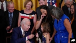 Predsednik Bajden poklanja Briel Robinson, ćerki američkog vojnika koji je preminuo od raka, olovku kojom je potpisao zakon o zdravstvenoj zaštiti američkih veterana. 10. avgusta 2022.