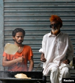 Pria melemparkan adonan saat memasak puri, roti pipih goreng tradisional, di pasar pagi di Karachi 26 Juli 2009. Puri, yang merupakan hidangan populer di Asia Selatan, dikonsumsi sebagian besar saat sarapan. (REUTERS/Akhtar Soomro)