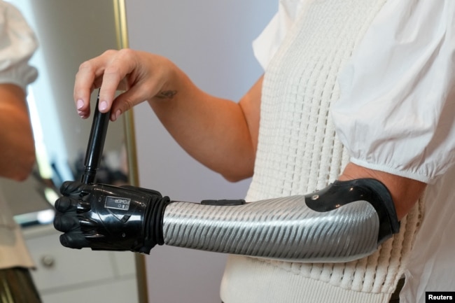 Jessica Smith, a former Australian Paralympic Swimmer, poses for a picture while applying make-up with her new bionic hand that improves the speed of movement and sensitivity of touch, according to the company, in London, Britain August 12, 2022. (REUTERS)