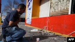 A man prays in front of a building where unknown persons burned shops in Ciudad Juarez, Chihuahua, Mexico, Aug. 12, 2022.