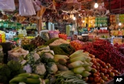 Seorang pedagang sayur dan rempah-rempah menunggu pelanggan di kiosnya di pasar tradisional di Tangerang, Indonesia, Selasa, 29 Maret 2022. (Tatan Syuflana/AP)