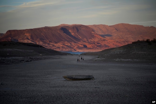 FILE - A formerly sunken boat sits on cracked earth hundreds of feet from what is now the shoreline on Lake Mead on May 9, 2022, near Boulder City, Nevada. Two sets of human remains emerged from the drought-stricken Colorado River reservoir just a short drive from Las Vegas, Nevada. (AP Photo/John Locher)