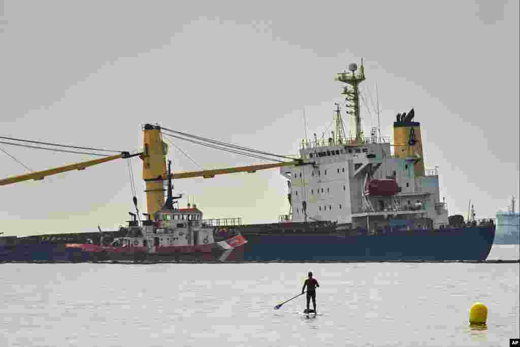 A man walks with his paddle surf board to get a closer look at the Tuvalu-registered OS 35 cargo ship lying on the seabed, offshore Gibraltar. Authorities said they have beached a cargo ship to prevent it from sinking after it collided with a liquid natural gas carrier in the bay of Gibraltar.