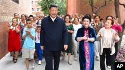 FILE - In this photo released by China's Xinhua News Agency, Chinese President Xi Jinping, center, visits the community of Guyuanxiang in the Tianshan District in Urumqi in northwestern China's Xinjiang Uyghur Autonomous Region, July 13, 2022. 