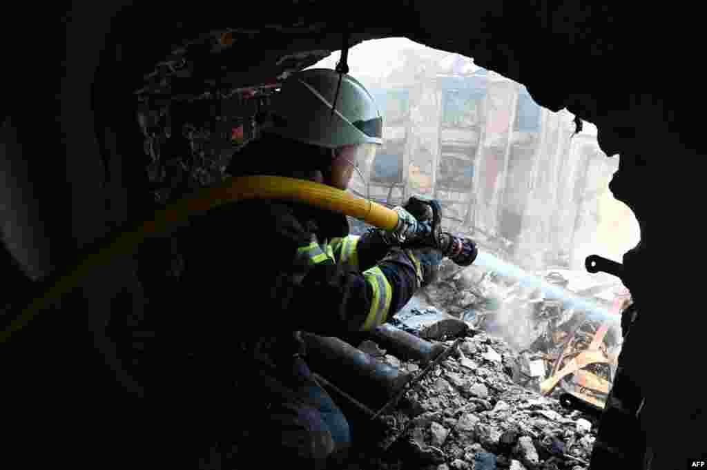 A firefighter douses the rubble of the Culture Palace destroyed by Russian missile strike in the Ukrainian city of Kharkiv.