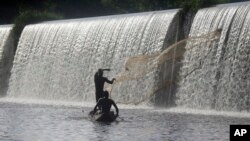 FILE: Fishermen cast a net near a dam that sources the Osun River in Esa-Odo, Nigeria, on May 28, 2022.