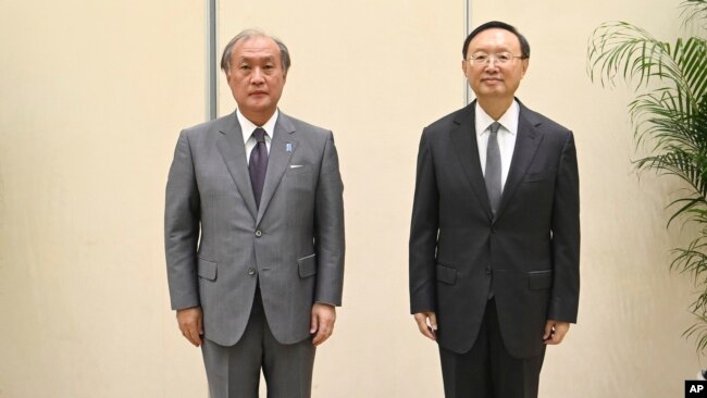 In this photo released by Xinhua News Agency, Yang Jiechi, right, a member of the Political Bureau of the Communist Party of China (CPC) Central Committee, poses for photos with Akiba Takeo, head of Japan's National Security Secretariat, in northern China, Aug. 17, 2022.