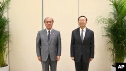 In this photo released by Xinhua News Agency, Yang Jiechi, right, a member of the Political Bureau of the Communist Party of China (CPC) Central Committee poses with Akiba Takeo, head of Japan's National Security Secretariat, in northern China, Aug. 17, 2022. 