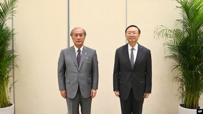 In this photo released by Xinhua News Agency, Yang Jiechi, right, a member of the Political Bureau of the Communist Party of China (CPC) Central Committee poses with Akiba Takeo, head of Japan's National Security Secretariat, in northern China, Aug. 17, 2022.
