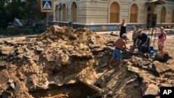 Local residents take water from a partially restored water supply in a crater after an air bomb hit in Bakhmut, Donetsk region, Ukraine, Aug. 31, 2022. 