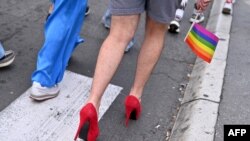 FILE - A participant holding a gay pride flag walks in high heels during a pride march, in Belgrade, Serbia, September 18, 2021. 