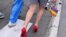 FILE - A participant holding a gay pride flag walks in high heels during a pride march, in Belgrade, Serbia, September 18, 2021. 