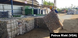 Pekerja Bangoan Bumi Lestari, Tulungagung, Jawa Timur, menumpuk botol plastik yang telah diproses sebelum dikirim ke pabrik daur ulang plastik. (Foto: VOA/Petrus Riski)