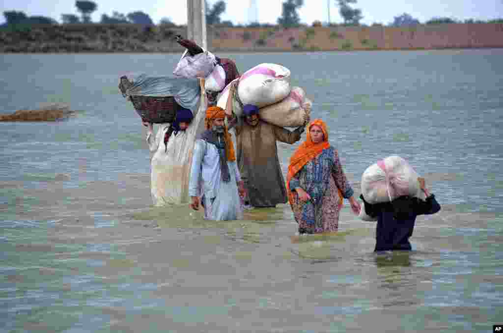 A displaced family wades through a flooded area after heavy rainfall, in Jaffarabad, a district of Pakistan's southwestern Baluchistan province.