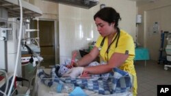 FILE - A medical worker takes care of a newborn baby who couldn't be evacuated to a bomb shelter, in a hospital damaged during shelling in Donetsk, in eastern Ukraine, June 14, 2022. 