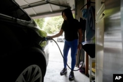 Monique An charges her Tesla car to a wall connector charger while posing for photos at her home in San Francisco, Thursday, Aug. 25, 2022. (AP Photo/Jeff Chiu)
