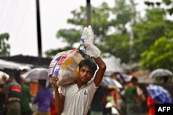 A Rohingya refugee walks back to his house after collecting relief material in Kutupalong refugee camp in Ukhia on August 10, 2022. (Photo by Munir uz Zaman / AFP)